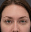 Close-up of a person's face with brown hair and green eyes.