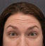 Close-up of a person's face with a neutral expression on a gray background