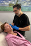 Doctor examining a patient's neck with a tropical beach mural in the background