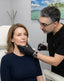 Woman receiving a cosmetic procedure from a professional in a clinical setting.