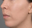 Close-up of a person's ear and side of their face with a neutral background